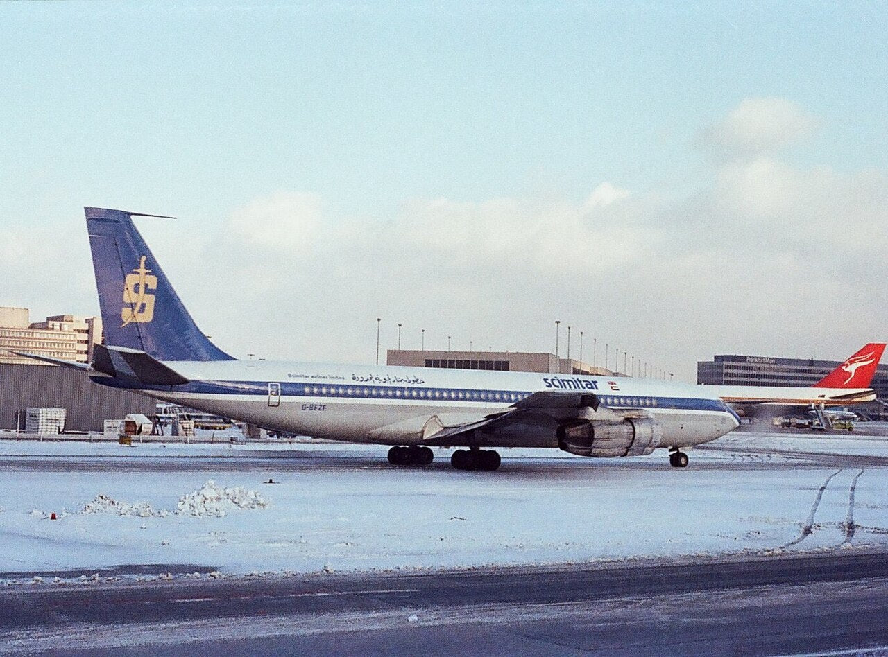 Side view of a blue-and-white Boeing 707-321C G-BFZF parked on a snowy apron; the nose, tail, visible wings, engine nacelles and landing gear lie inside the frame.