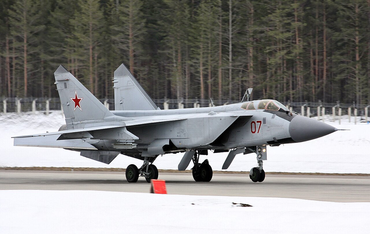 Grey MiG-31 seen from the side, with pointed nose, two-seat canopy, large rectangular intake and twin fins.