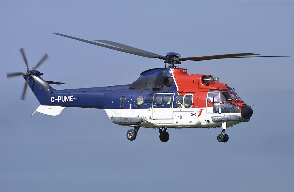Side view of red, white and blue Super Puma G-PUME in flight, with the complete visible rotors, tail and landing gear.