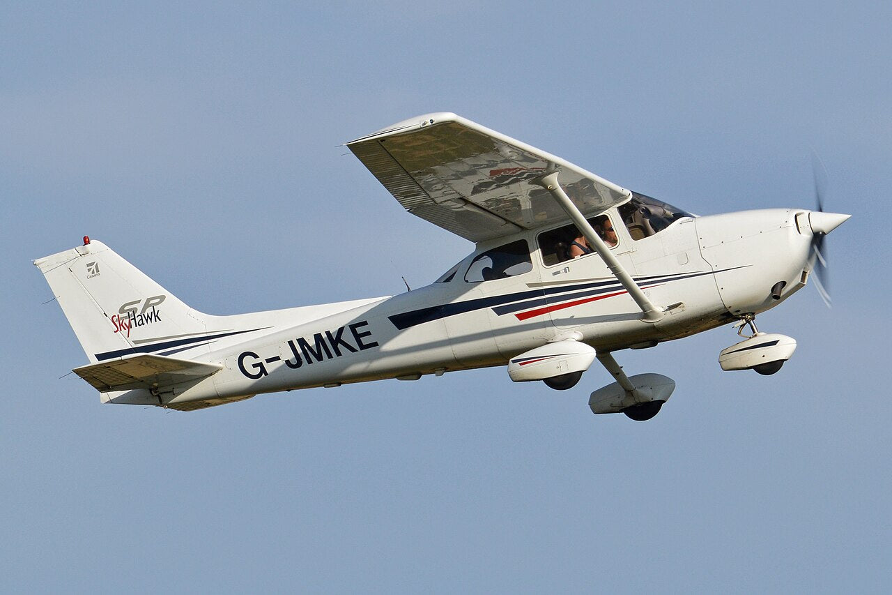 White Cessna 172S G-JMKE in flight, seen from the side and below, with a high wing and fixed landing gear.