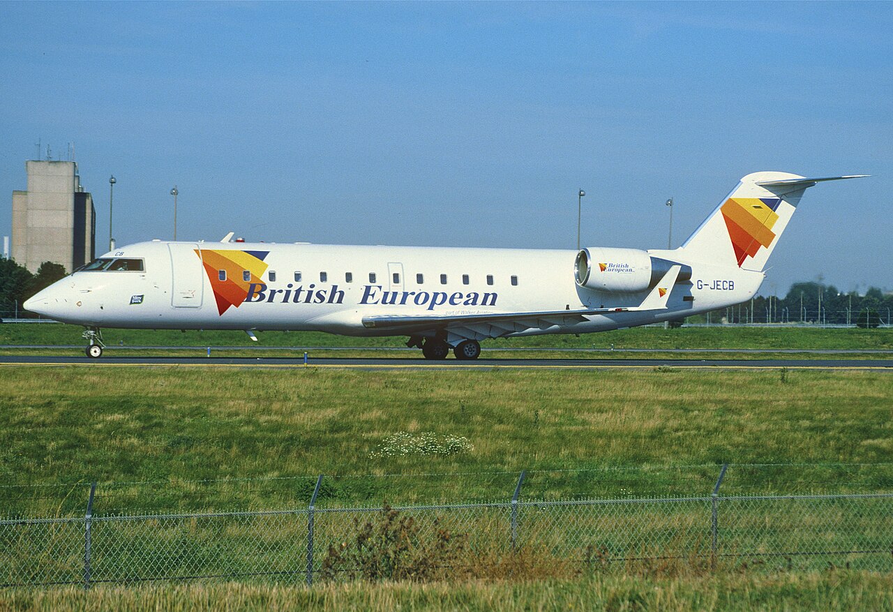 British European Bombardier CRJ200 G-JECB on the ground, viewed from the side with its nose, wings, rear-mounted engines and T-tail visible.