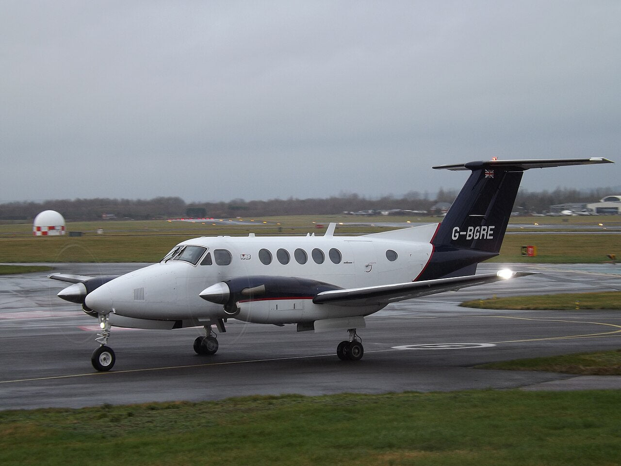 Beech 200 G-BGRE seen from the front and side, with two propellers, a high horizontal tail and its landing gear down.
