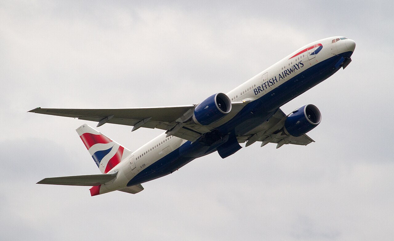 British Airways Boeing 777-236 G-VIIA climbing after takeoff, seen from below with both large underwing engines visible.