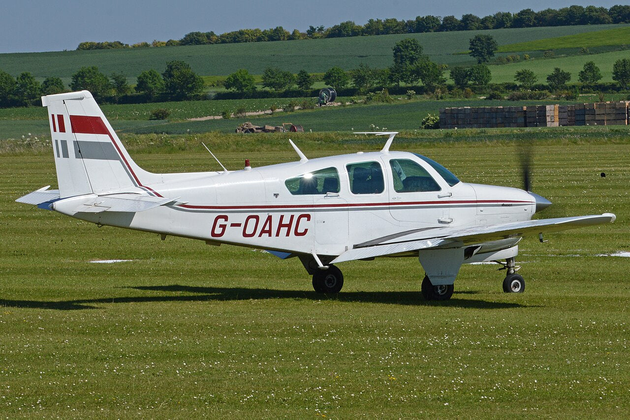 White-and-red F33C Bonanza G-OAHC on the ground, showing its conventional fin and horizontal tail; this is not a V-tail V35B.