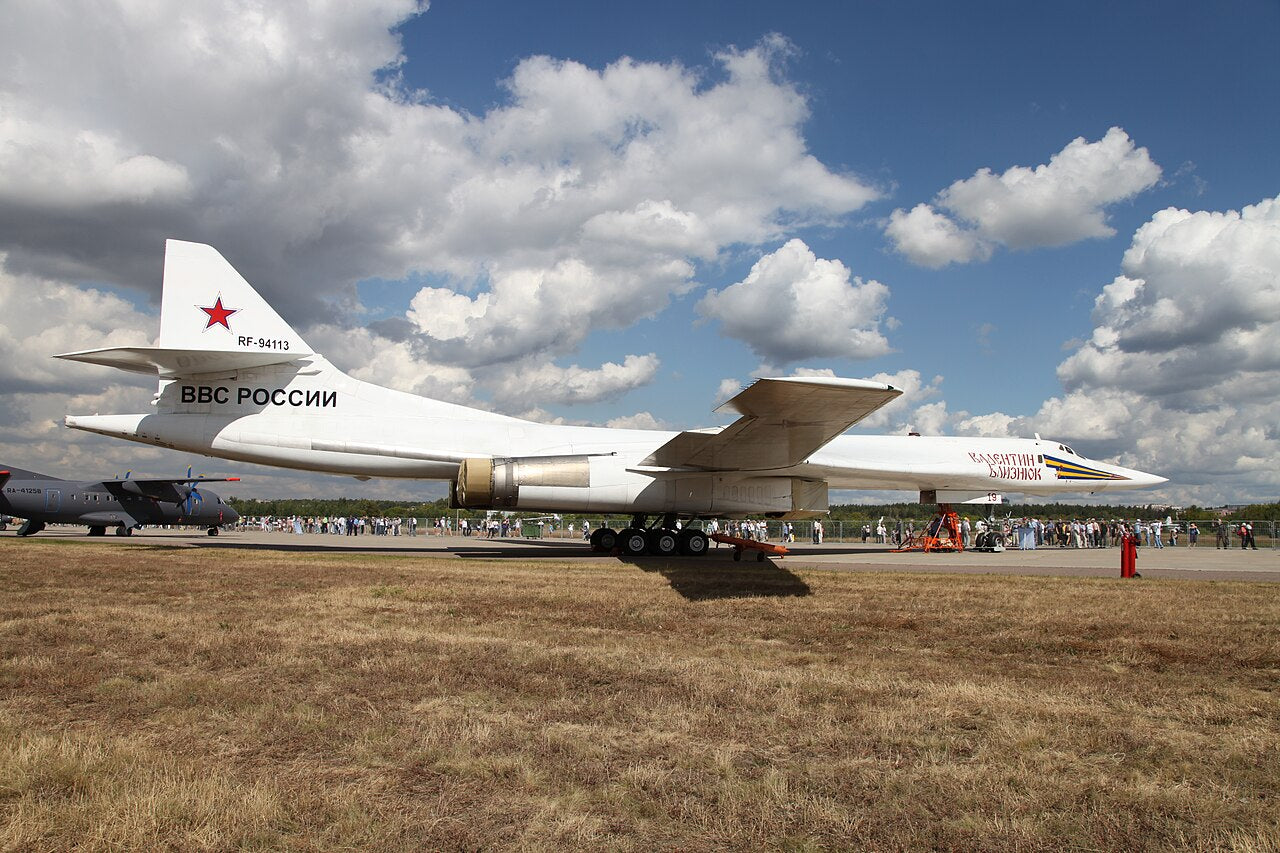 White Tu-160 RF-94113 seen from the side on the ground, with long pointed nose, wing, engine exhausts and swept tail fin.