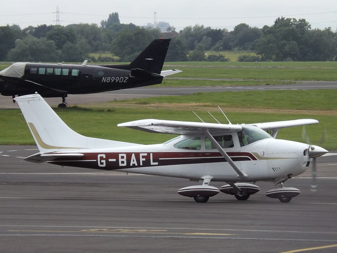 White-and-red Cessna 182P Skylane G-BAFL seen from the side at Gloucestershire Airport, with a high wing and fixed landing gear.