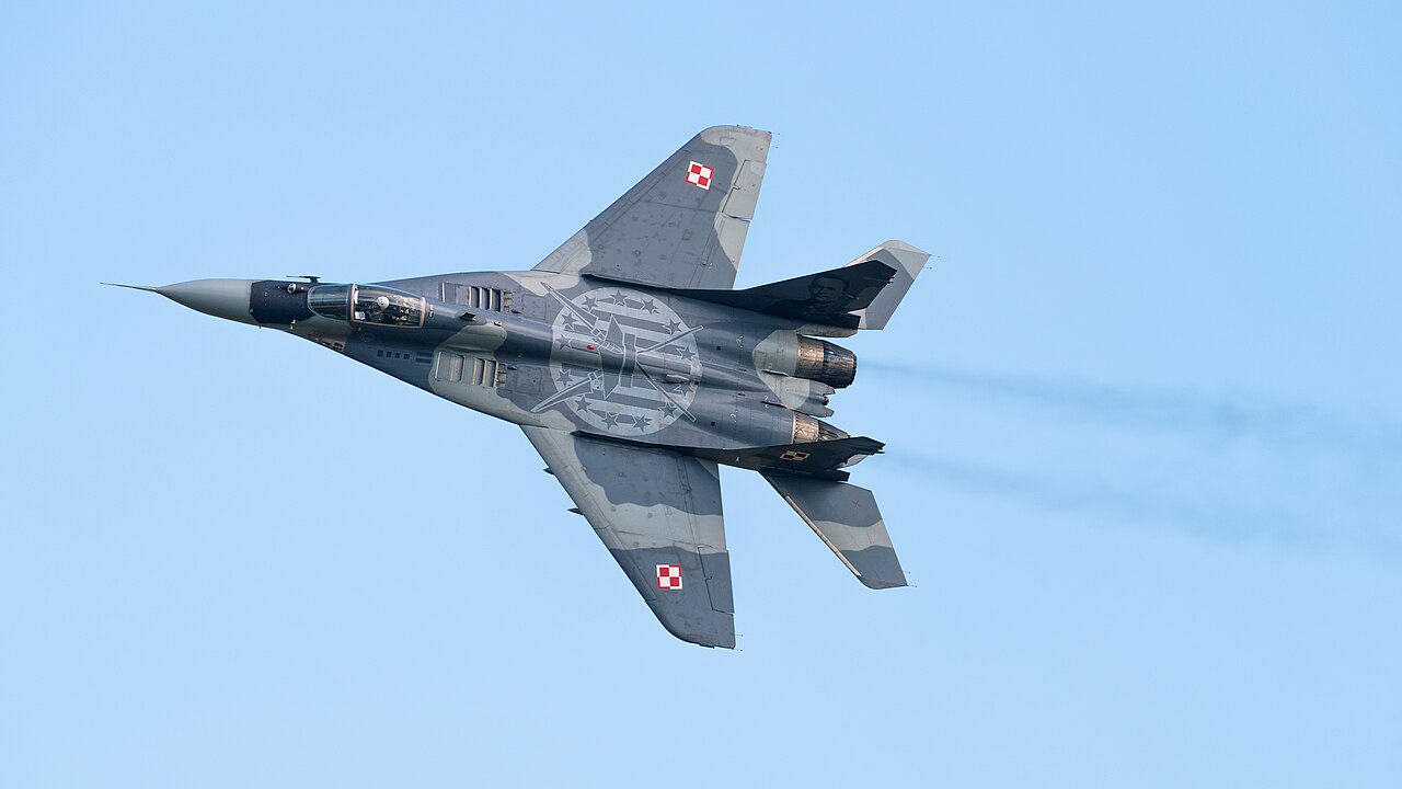 Whole-airframe upper view of a Polish MiG-29A banking against blue sky, showing its swept wings, twin engines and twin tail fins.